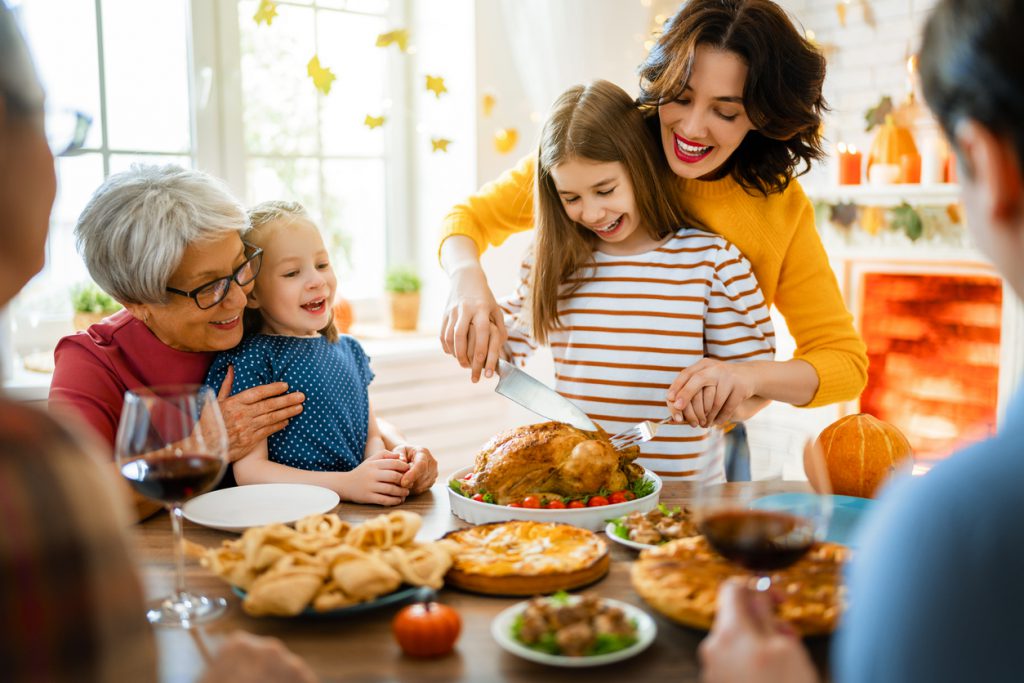 Happy Thanksgiving Day! Autumn feast. The family- grandparents, mother, father, and children- sit at the table celebrating the holiday. Traditional dinner.